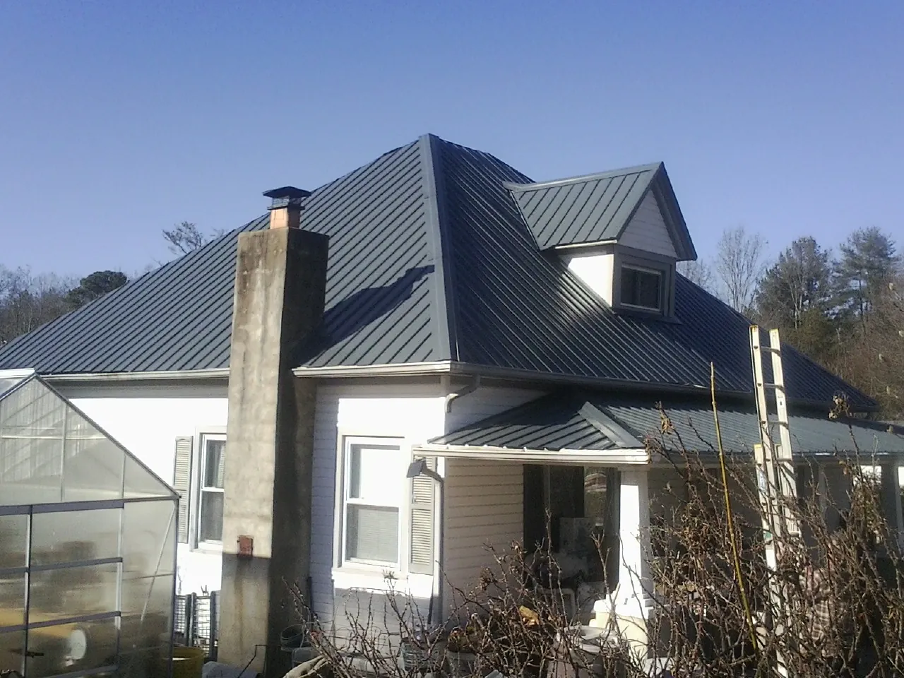 Dark blue standing seam metal roof on a white farmhouse with dormer — Slate & Tile Roof Repair by Roofing Brothers in Callensburg