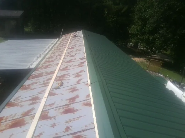 Old rusted panels beside newly installed green metal roofing — Wind Damage Roof Repair by Roofing Brothers in Callensburg