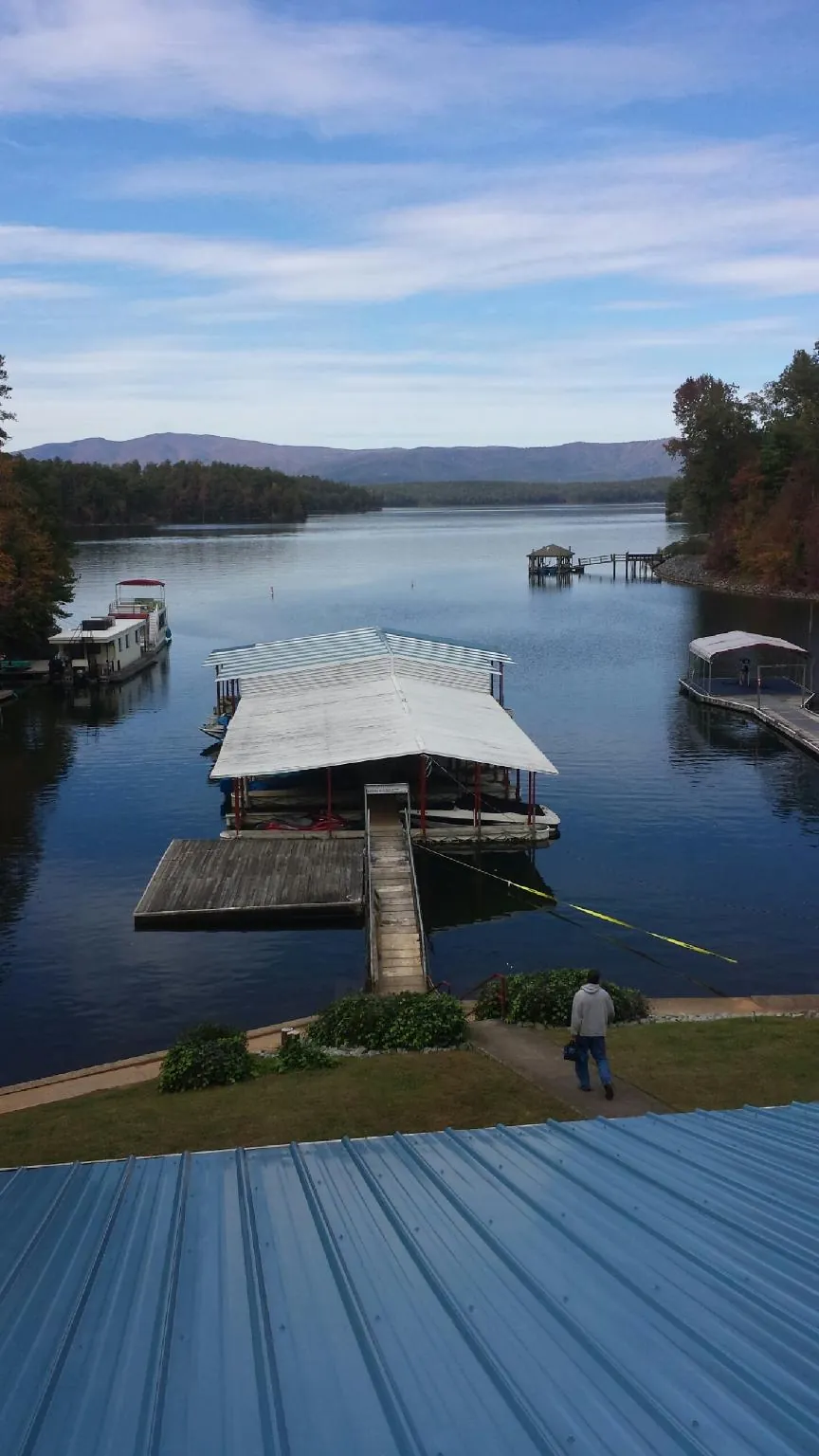 View across a lake from a newly installed blue metal roof in Callensburg