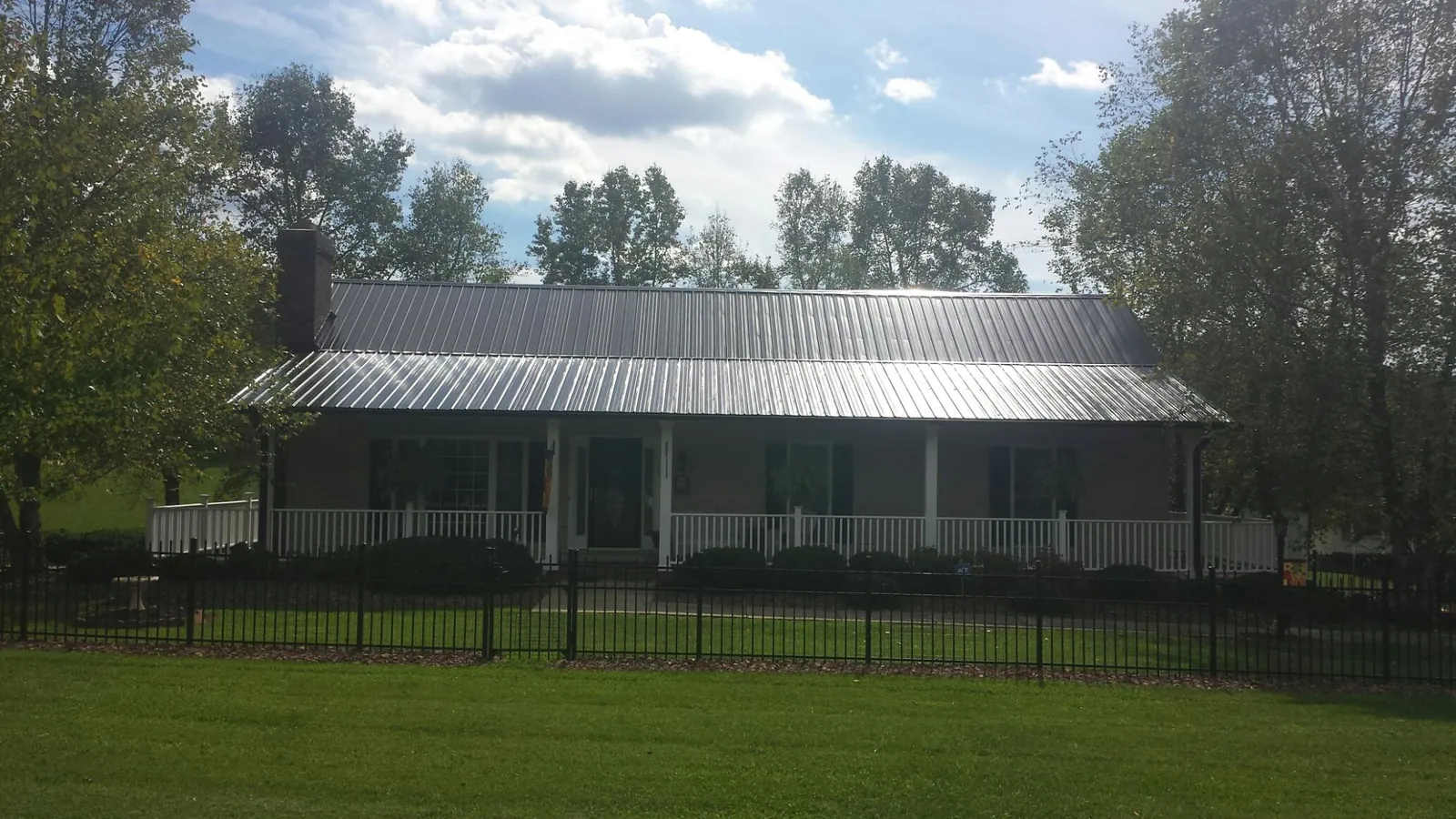 Gray metal roof on a brick ranch with a full width front porch — Gutter Guard Installation work by our crew in Callensburg