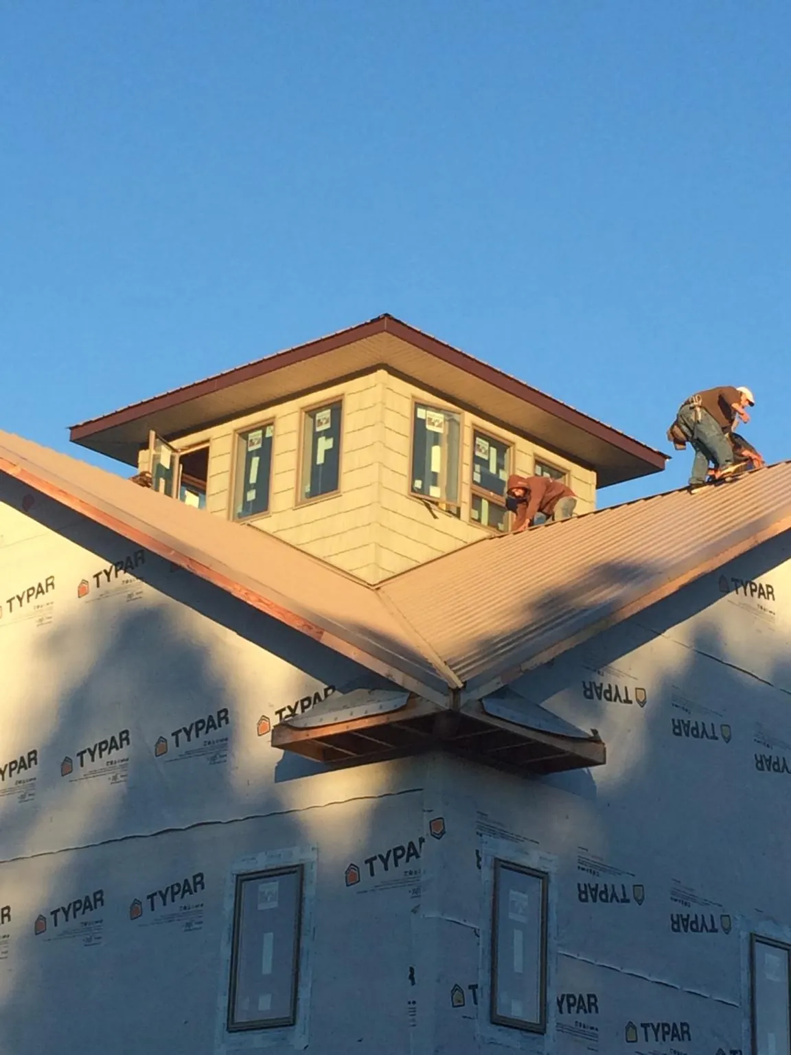 Roofers working around a rooftop cupola on a new metal roof at sunset — Roof Waterproofing in Callensburg by Roofing Brothers